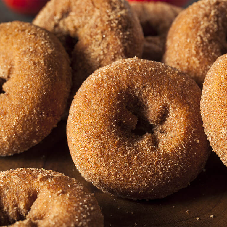 Close-up of cinnamon sugar donuts stacked together, highlighting their round shape and sugary coating.